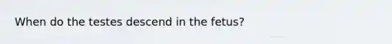 When do the testes descend in the fetus?