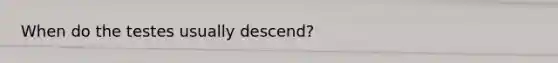 When do the testes usually descend?