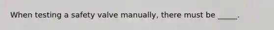 When testing a safety valve manually, there must be _____.