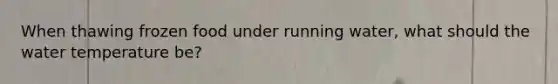 When thawing frozen food under running water, what should the water temperature be?