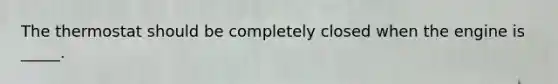 The thermostat should be completely closed when the engine is _____.
