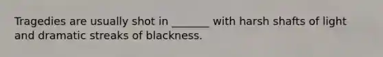 Tragedies are usually shot in _______ with harsh shafts of light and dramatic streaks of blackness.