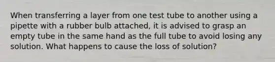 When transferring a layer from one test tube to another using a pipette with a rubber bulb attached, it is advised to grasp an empty tube in the same hand as the full tube to avoid losing any solution. What happens to cause the loss of solution?