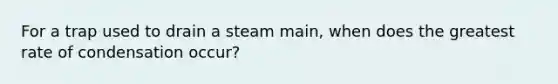 For a trap used to drain a steam main, when does the greatest rate of condensation occur?