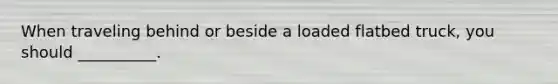 When traveling behind or beside a loaded flatbed truck, you should __________.