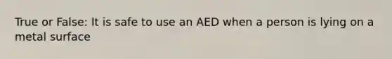 True or False: It is safe to use an AED when a person is lying on a metal surface