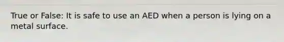 True or False: It is safe to use an AED when a person is lying on a metal surface.