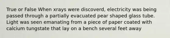 True or False When xrays were discoverd, electricity was being passed through a partially evacuated pear shaped glass tube. Light was seen emanating from a piece of paper coated with calcium tungstate that lay on a bench several feet away