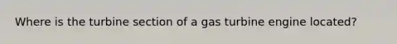 Where is the turbine section of a gas turbine engine located?