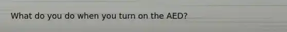 What do you do when you turn on the AED?