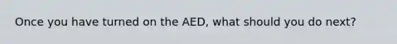 Once you have turned on the AED, what should you do next?