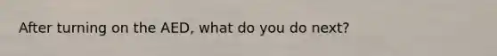 After turning on the AED, what do you do next?