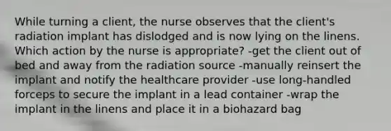 While turning a client, the nurse observes that the client's radiation implant has dislodged and is now lying on the linens. Which action by the nurse is appropriate? -get the client out of bed and away from the radiation source -manually reinsert the implant and notify the healthcare provider -use long-handled forceps to secure the implant in a lead container -wrap the implant in the linens and place it in a biohazard bag