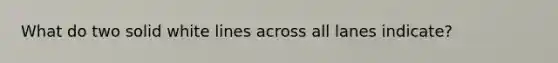 What do two solid white lines across all lanes indicate?