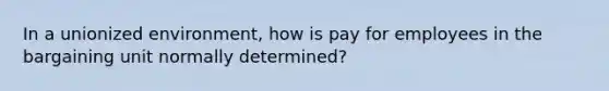 In a unionized environment, how is pay for employees in the bargaining unit normally determined?