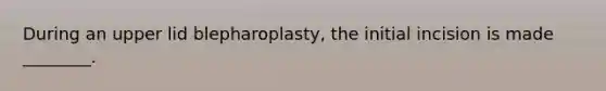 During an upper lid blepharoplasty, the initial incision is made ________.