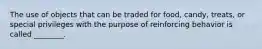 The use of objects that can be traded for food, candy, treats, or special privileges with the purpose of reinforcing behavior is called ________.