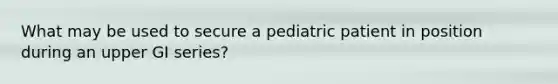 What may be used to secure a pediatric patient in position during an upper GI series?