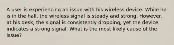 A user is experiencing an issue with his wireless device. While he is in the hall, the wireless signal is steady and strong. However, at his desk, the signal is consistently dropping, yet the device indicates a strong signal. What is the most likely cause of the issue?