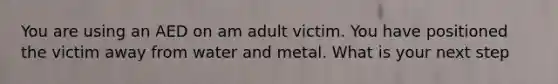 You are using an AED on am adult victim. You have positioned the victim away from water and metal. What is your next step