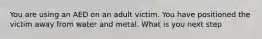 You are using an AED on an adult victim. You have positioned the victim away from water and metal. What is you next step