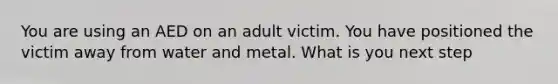 You are using an AED on an adult victim. You have positioned the victim away from water and metal. What is you next step