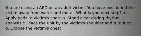 You are using an AED on an adult victim. You have positioned the victim away from water and metal. What is you next step? a. Apply pads to victim's chest b. Stand clear during rhythm analysis c. Place the unit by the victim's shoulder and turn it on d. Expose the victim's chest