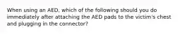 When using an AED, which of the following should you do immediately after attaching the AED pads to the victim's chest and plugging in the connector?