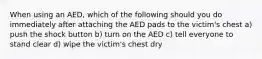 When using an AED, which of the following should you do immediately after attaching the AED pads to the victim's chest a) push the shock button b) turn on the AED c) tell everyone to stand clear d) wipe the victim's chest dry