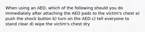 When using an AED, which of the following should you do immediately after attaching the AED pads to the victim's chest a) push the shock button b) turn on the AED c) tell everyone to stand clear d) wipe the victim's chest dry