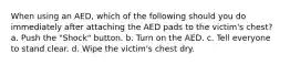 When using an AED, which of the following should you do immediately after attaching the AED pads to the victim's chest? a. Push the "Shock" button. b. Turn on the AED. c. Tell everyone to stand clear. d. Wipe the victim's chest dry.