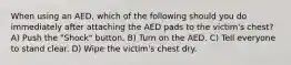 When using an AED, which of the following should you do immediately after attaching the AED pads to the victim's chest? A) Push the "Shock" button. B) Turn on the AED. C) Tell everyone to stand clear. D) Wipe the victim's chest dry.