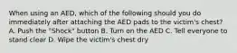 When using an AED, which of the following should you do immediately after attaching the AED pads to the victim's chest? A. Push the "Shock" button B. Turn on the AED C. Tell everyone to stand clear D. Wipe the victim's chest dry