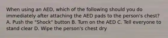 When using an AED, which of the following should you do immediately after attaching the AED pads to the person's chest? A. Push the "Shock" button B. Turn on the AED C. Tell everyone to stand clear D. Wipe the person's chest dry