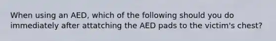 When using an AED, which of the following should you do immediately after attatching the AED pads to the victim's chest?