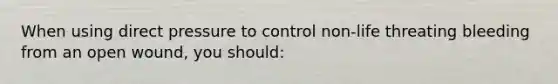 When using direct pressure to control non-life threating bleeding from an open wound, you should: