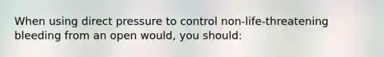 When using direct pressure to control non-life-threatening bleeding from an open would, you should: