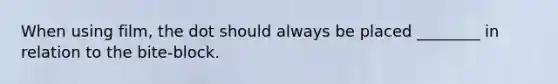 When using film, the dot should always be placed ________ in relation to the bite-block.