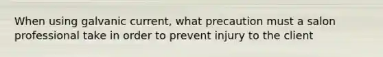 When using galvanic current, what precaution must a salon professional take in order to prevent injury to the client