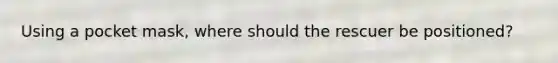 Using a pocket mask, where should the rescuer be positioned?