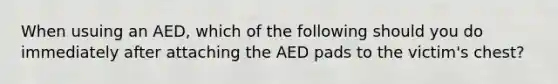 When usuing an AED, which of the following should you do immediately after attaching the AED pads to the victim's chest?