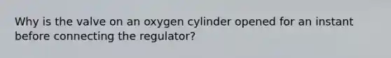 Why is the valve on an oxygen cylinder opened for an instant before connecting the regulator?