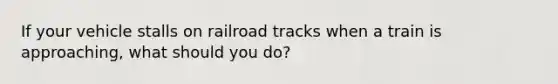 If your vehicle stalls on railroad tracks when a train is approaching, what should you do?