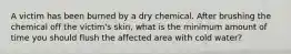 A victim has been burned by a dry chemical. After brushing the chemical off the victim's skin, what is the minimum amount of time you should flush the affected area with cold water?