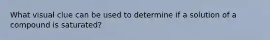 What visual clue can be used to determine if a solution of a compound is saturated?