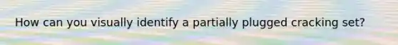 How can you visually identify a partially plugged cracking set?