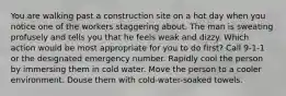 You are walking past a construction site on a hot day when you notice one of the workers staggering about. The man is sweating profusely and tells you that he feels weak and dizzy. Which action would be most appropriate for you to do first? Call 9-1-1 or the designated emergency number. Rapidly cool the person by immersing them in cold water. Move the person to a cooler environment. Douse them with cold-water-soaked towels.