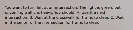 You want to turn left at an intersection. The light is green, but oncoming traffic is heavy. You should: A. Use the next intersection. B. Wait at the crosswalk for traffic to clear. C. Wait in the center of the intersection for traffic to clear.