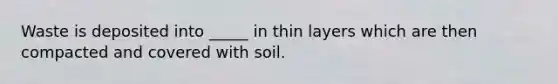 Waste is deposited into _____ in thin layers which are then compacted and covered with soil.