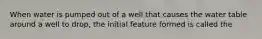 When water is pumped out of a well that causes the water table around a well to drop, the initial feature formed is called the